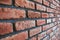 Side angle of a red brick wall. Close up view of cracked weathered cemented brickwork material. Modern interior design, unique