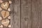 Side border of handmade burlap heart decorations over rustic wood