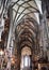 Side of the central nave of the Vienna Cathedral looking towards the altar and ending with the large window from which daylight co