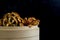 Side of cinnamon cap mushroom spilling out in bamboo bowl on dark background