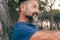 Side closeup portrait of adult man with beard smiling and enjoying relax time at the park. Happy and serene people with cheerful