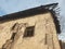 Side facade of an old rotten abandoned building with broken windows and peeling stucco