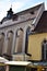 Side of Graz Cathedral, with stalls at the base and blue sky, veiled with white clouds, above.