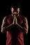 Side lit muscular Caucasian man silhouette. Athlete in red shirt praying against black background