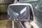 Side mirror of old abandoned rusty vehicles, crushed cars in scrapyard, junk yard needed to be utilised and reused to