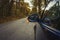 Side mirror turn signal. Turn indicator on the mirror left and blue car on the road in autumn forest. Car stands on the edge of