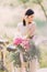 The side photo of the blurred bride holding her dark hair in the white wedding dress near the blurred bicycle with the