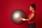 Side portrait of a beautiful sportswoman exercising with fitness ball while doing a functional cross and body weight training for
