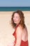 Side portrait of curly brunette forties woman in sand ocean beach