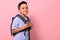 Side portrait of a smiling with toothy smile schoolboy with a school bag on his back on pink background with copy space. Back to