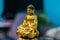 Side profile shot of a golden Buddha statue in close up using prime lens with blurred blue wall behind