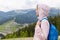 Side profile view of attractive beautiful girl, wearing casual rose jacket and blue rucksack, female backpacking and wandering.