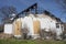 Side of residential home burned out by fire plywood boarded windows roof chared