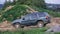 Side shot of blue jeep speeding through artificial obstacles