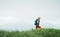 Side shot of hiker man walking by the foggy cloudy weather mountain range path with backpack. Active sport backpacking healthy