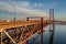 side view of the 25 de Abril bridge towards Almada-Lisboa with the Tagus River on the right and the capital of Portugal.