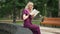 Side view absorbed female reader sitting at fountain in city park turning book pages in slow motion. Happy relaxed