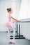 side view of adorable little ballerina in pink tutu exercising