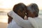 Side view of affectionate newlywed biracial senior bride and groom embracing during sunset