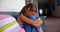 Side view of African American schoolgirl with head down sitting alone on bench in school corridor 4k