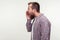 Side view of angry bearded man in casual shirt yelling loudly holding arm near mouth. studio shot isolated on white background