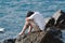 Side view of anxiety stressed Asian man hug his knee and sitting at sea shore.