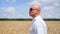 Side view of bald man going in the golden wheat field. Medium shot.