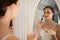 Side view of beautiful bride applying makeup reflecting on mirror