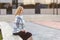 Side view of beautiful elegant successful businesswoman sitting on bench, looking aside with cute smile. outdoors