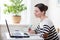 Side view a beautiful millennial mixed-race woman looks at a laptop screen, listens to an educational webinar