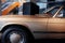 Side view of beige retro cabriolet car with chrome window trim and windshield washer, mirror, shiny hood, left door and