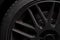 Side view of a black aluminum rim with rubber tire, dirty, dusty, break dust, picture shows a low key shot of a rim on dark black