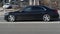 Side view of black Mercedes S-class car riding on the road on high speed. Shiny black sedan car in motion. Urban scene with riding