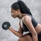 Side view of black teen girl working out with dumbbell.