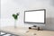 Side view on blank white monitor with copyspace for your text on wooden table with glass vase and keyboard, home office concept.