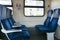 Side view of blue armchairs in empty train in row of three, no people in wagon, comfortable way of transportation,