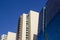 Side view of a blue curved modern corporate high-rise building, and two yellowish office buildings.