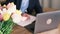 Side view of blurred business man in a suit writing something in a notebook next to an open laptop against the backdrop