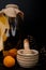 side view of bottle of apricot compote and garlic crusher with apricot and pinecones on wooden surface and black background