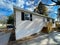 Side view of brand new prefab mobile home with for sale yard sign post in Rochester, New York