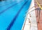 Side view of bright blue swimming pool with sparking crystal clear water and handrails