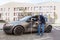 Side view of brunette male auto insurance adjuster inspecting a vehicle that has been in an accident wreck, wearing jeans and