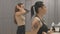 Side view of brunette tattooed woman talking with friend in dressing room after training. Portrait of adult sportive