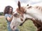 Side view of brunette woman stroking an american paint horse.