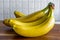 Side view of a bunch of yellow bananas which are laying on a wooden cutting board