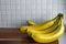 Side view of a bunch of yellow bananas which are laying on a wooden cutting board