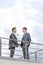 Side view of businessmen shaking hands at terrace railings against sky