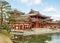 Side view of Byodoin Japanese buddhist temple under bright blue sky with clouds.