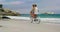 Side view of Caucasian couple riding a bicycle on the beach 4k