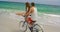 Side view of Caucasian couple riding a bicycle on the beach 4k